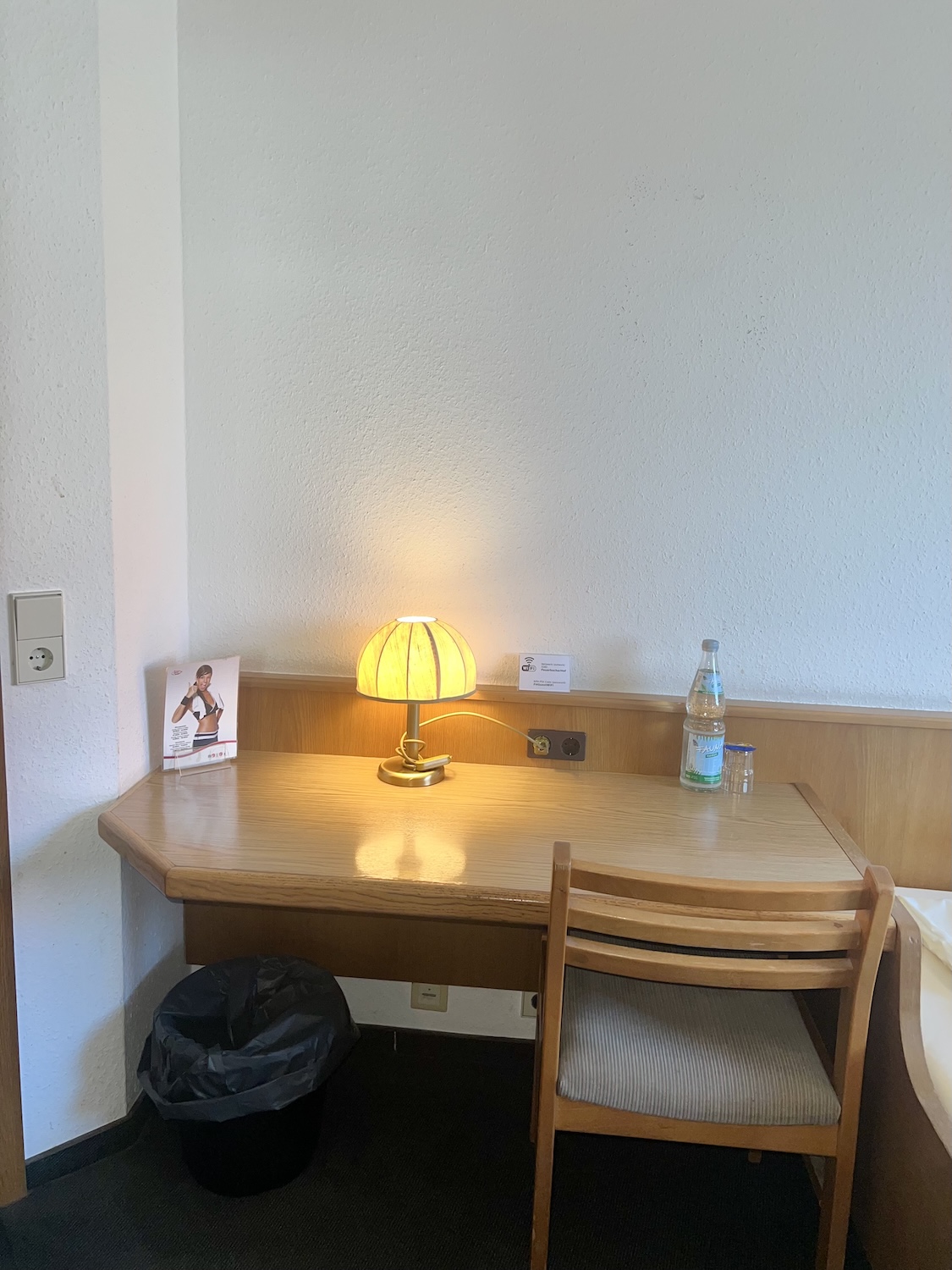 Schreibtisch im Einzelzimmer mit Lampe und WLAN-Hinweis